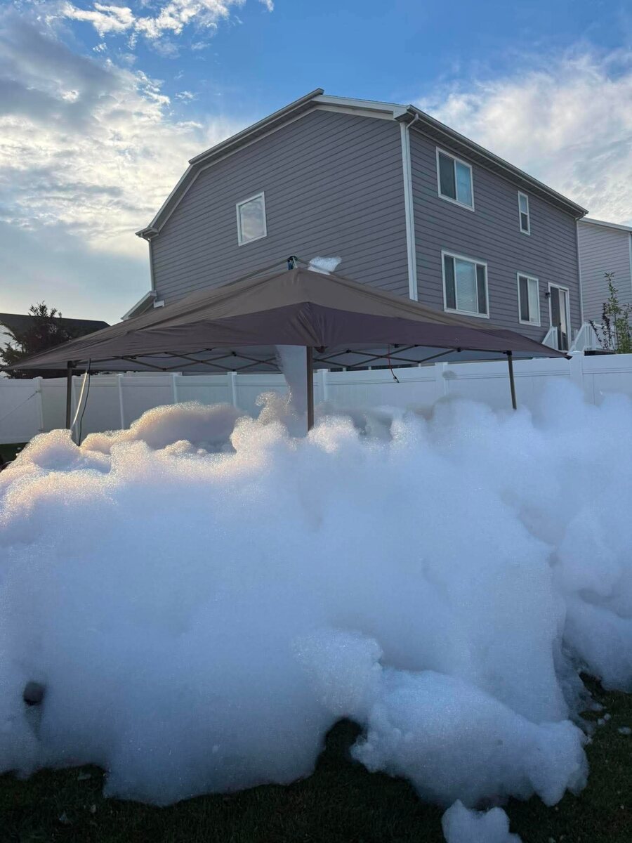 Foam piled taller than the backyard fence under a canopy